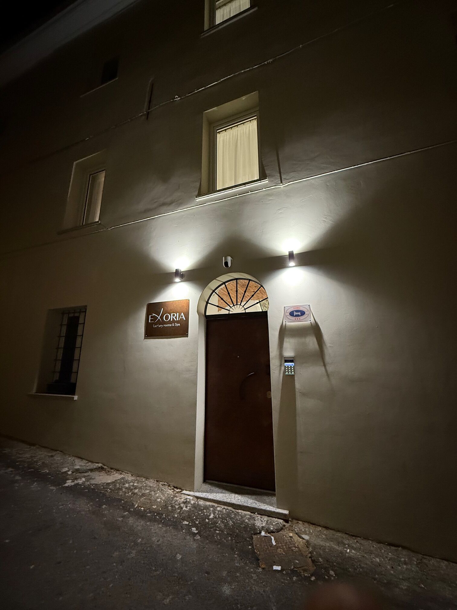 A building with a sign reading "EXORIA Luxury room & Spa" and a door with a security camera.
