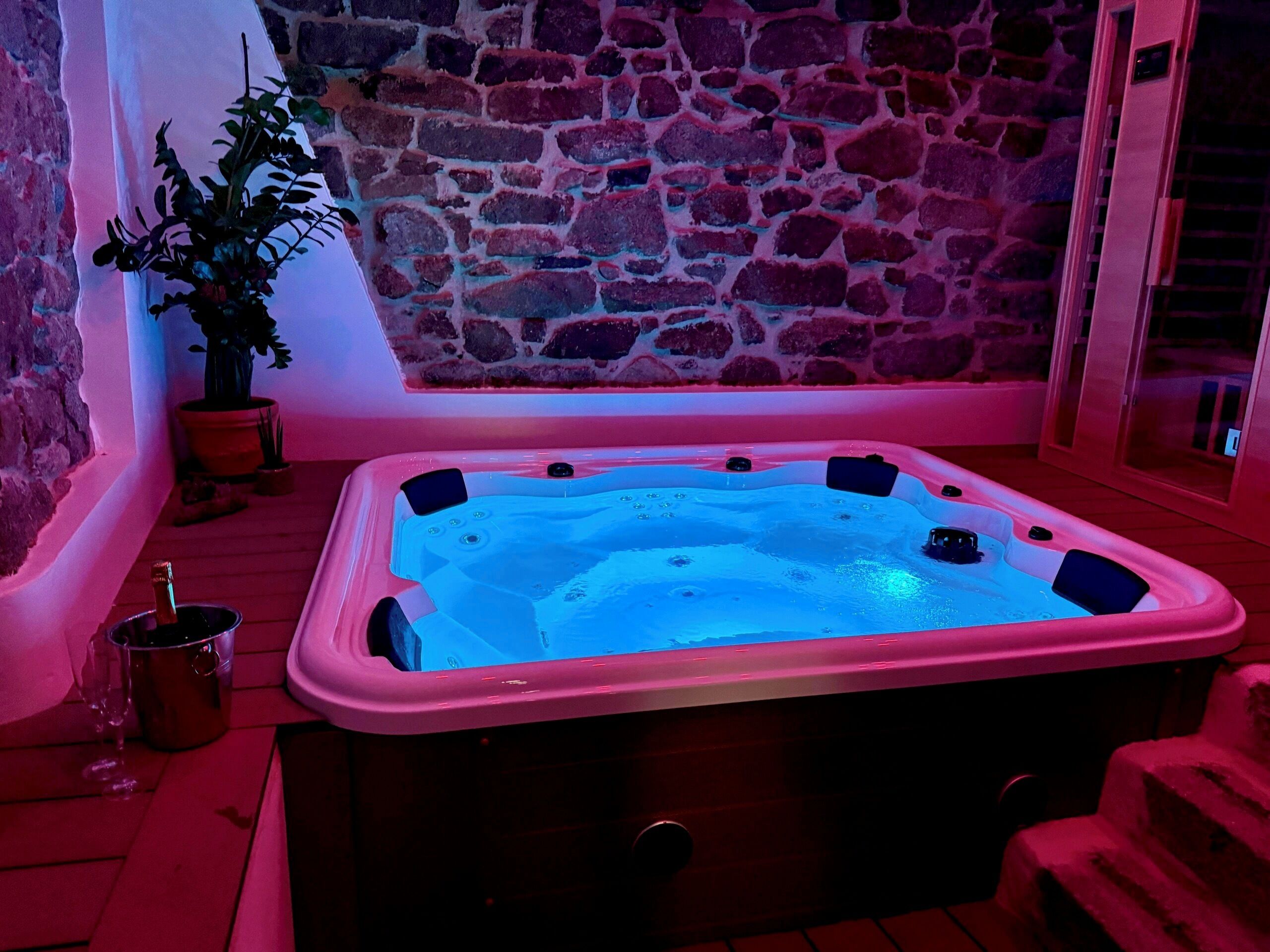 A hot tub in a room with stone walls and a wooden floor.