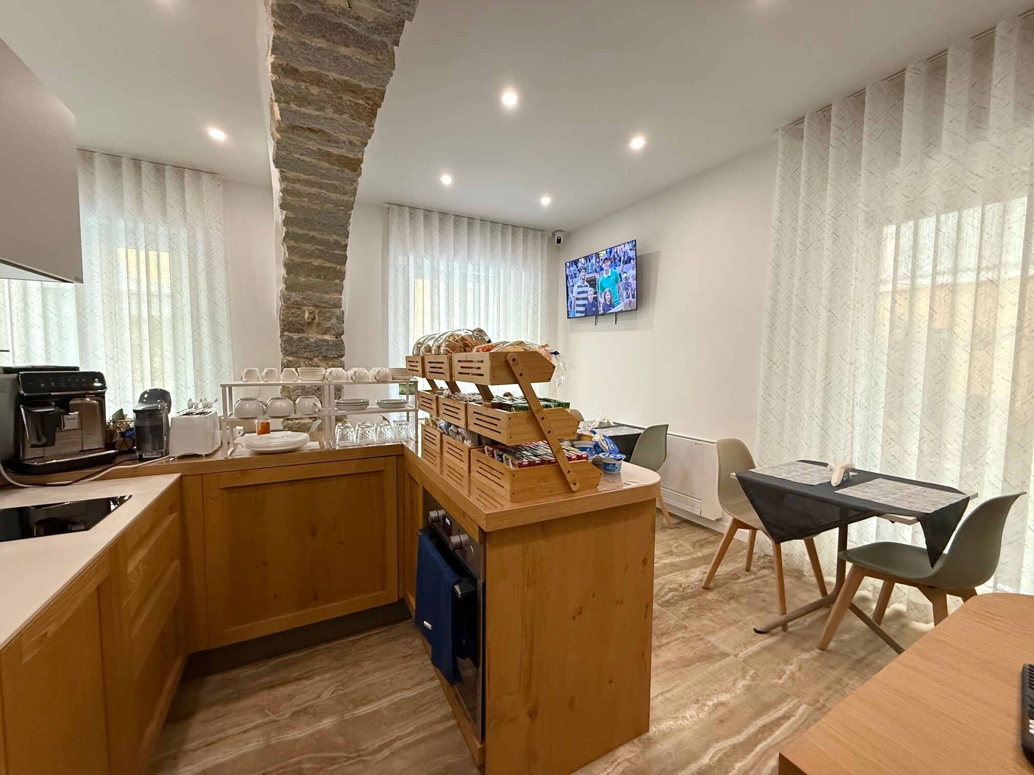 A modern kitchen with a stone accent wall, a coffee machine, and a breakfast bar with various items.