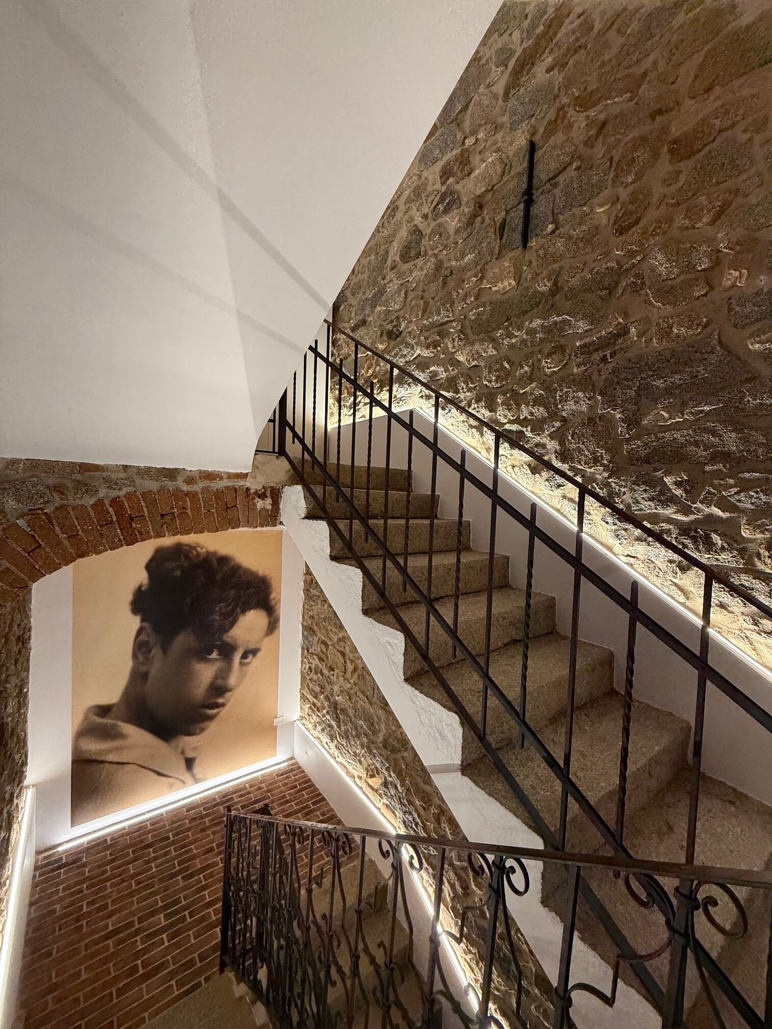 A staircase with a stone wall and a metal railing.