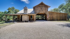 A rustic barn-style building with a stone chimney, wooden exterior, and a gravel driveway.