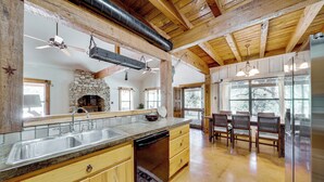 A kitchen with a stone fireplace, wooden cabinets, and a large island with a sink.