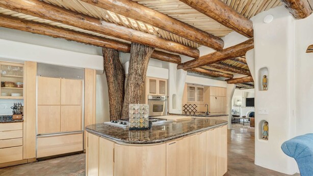 Una cocina amplia con armarios de madera, una isla central y un techo rústico con vigas a la vista.