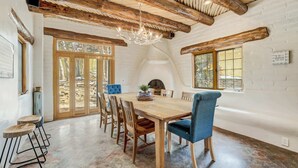 Un comedor rústico con una mesa de madera, sillas tapizadas en azul y una araña.