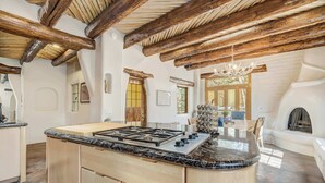 Una cocina con isla central, vigas de madera y una araña.