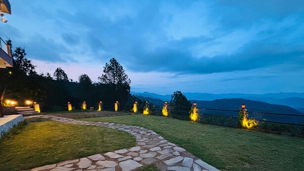 A stone pathway leading to a grassy area with a view of mountains in the background. - The Laylah - A Luxury villa in Binsar near Kasar Devi temple. (Kasardevi)