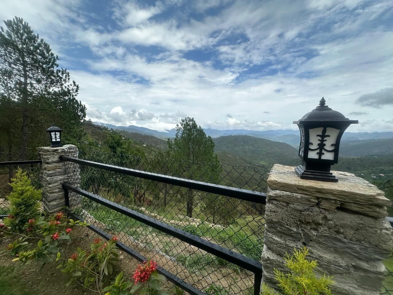 Una cerca de piedra con baranda de metal con vistas a un paisaje montañoso.