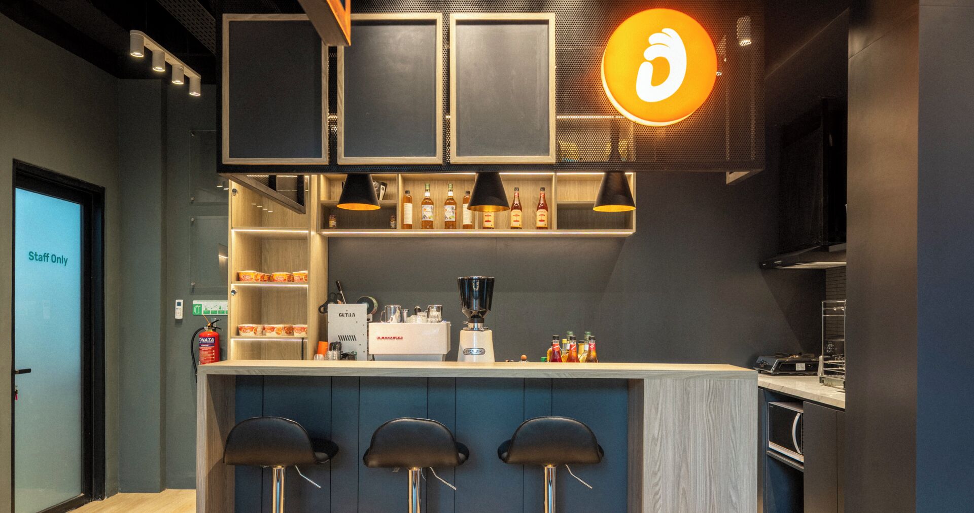 A modern bar area with a counter, stools, and a coffee machine.
