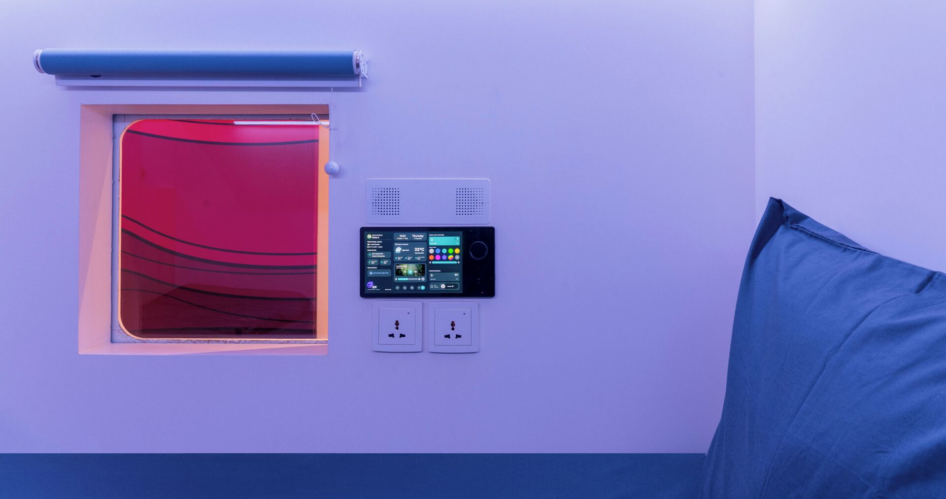 A room with a window, a control panel, and a blue pillow.