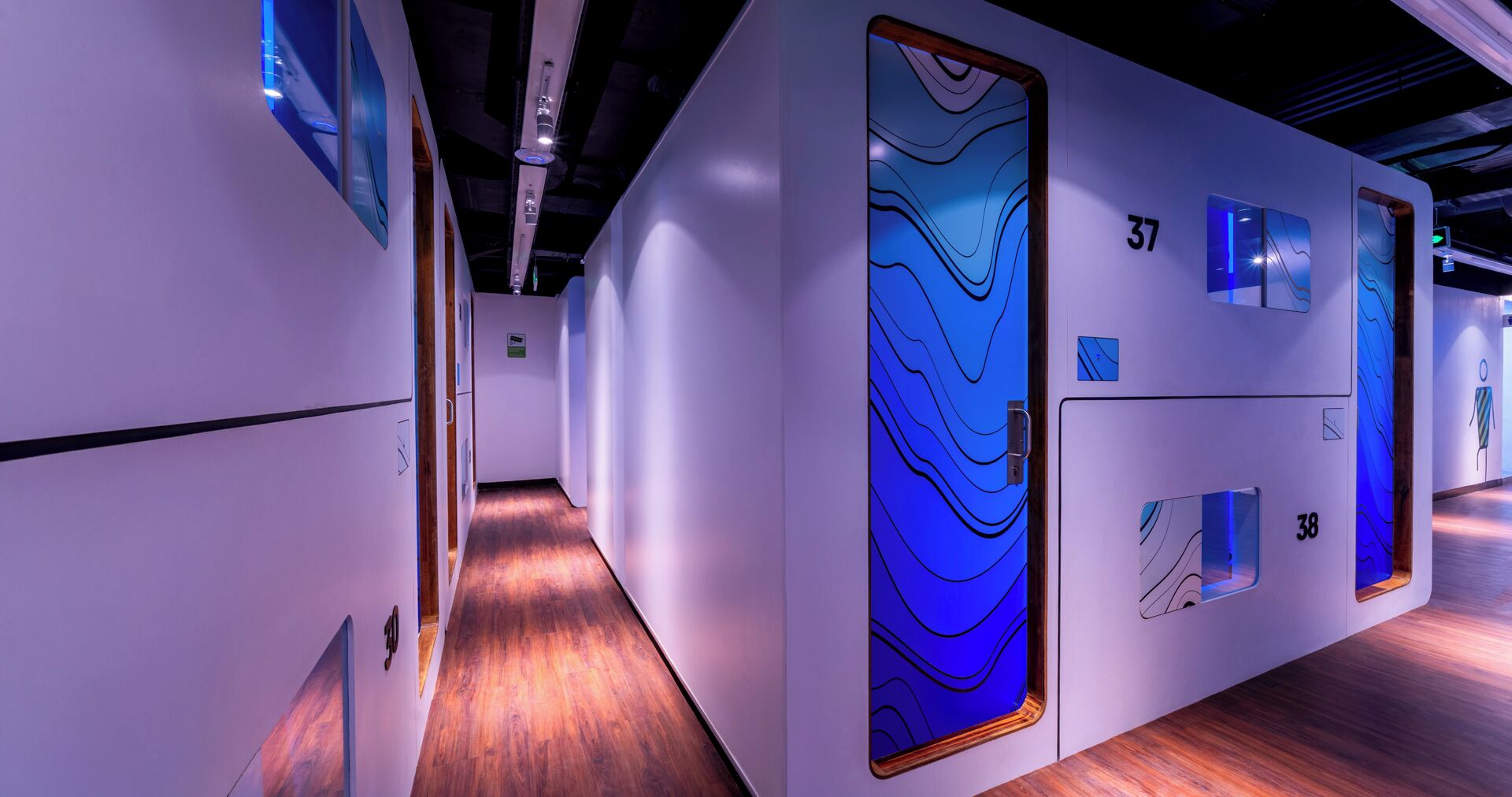A modern hotel corridor with wooden flooring and white walls.