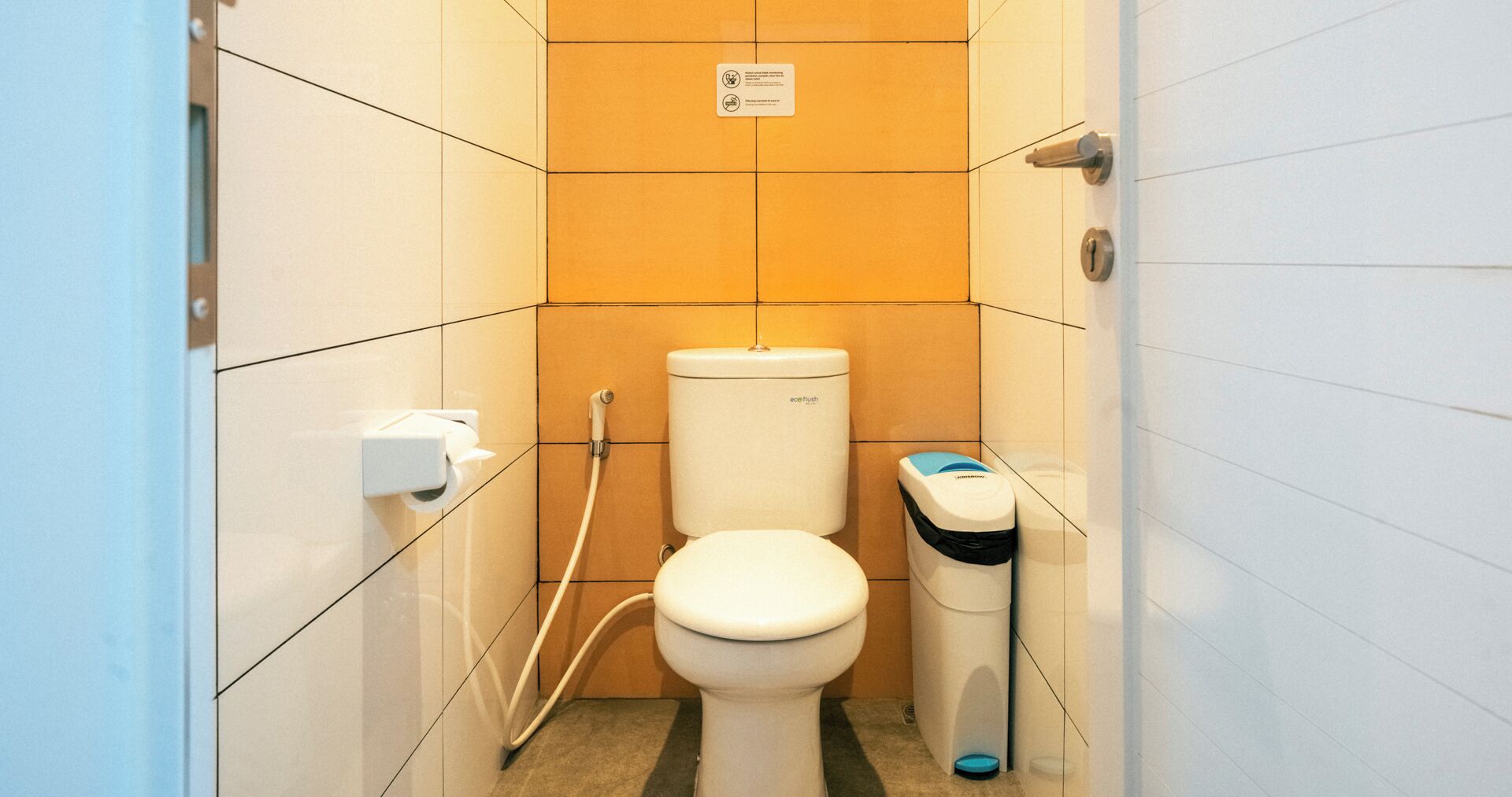A small, modern bathroom with a toilet, bidet, and trash bin.