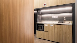 Una cocina compacta con microondas, fregadero y armarios.