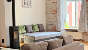 Un salon confortable avec un canapé, un lit, une cheminée et une fenêtre avec des rideaux.