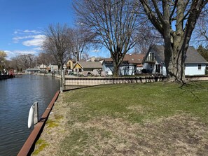 A riverside view with houses, a dock, and a grassy area.