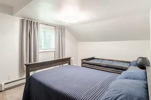 Une chambre avec un lit simple, une fenêtre avec des rideaux, un radiateur et une petite table de chevet.