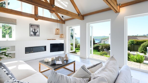A spacious living room with a high ceiling, wooden beams, a fireplace, a large TV, and a view of the countryside. - Point House - sleeps 8 guests  in 4 bedrooms (Charlestown,)