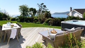 A wooden deck with outdoor furniture, a hot tub, and a view of the sea. - Point House - sleeps 8 guests  in 4 bedrooms (Charlestown,)