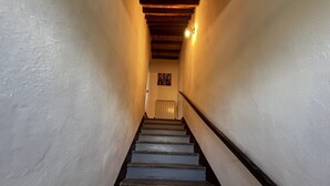 A staircase with wooden handrails and white walls, leading to a door at the top.