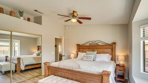 Een slaapkamer met een grote spiegel, een houten bed met hoofdeinde, bedlampjes en een bankje.