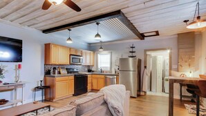 Una cocina moderna con armarios de madera, un refrigerador de acero inoxidable y un comedor con mesa y sillas.