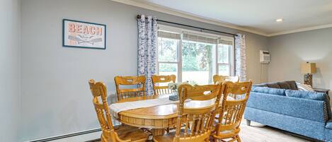 A dining area with a wooden table and chairs, a blue sofa, and a window with curtains.