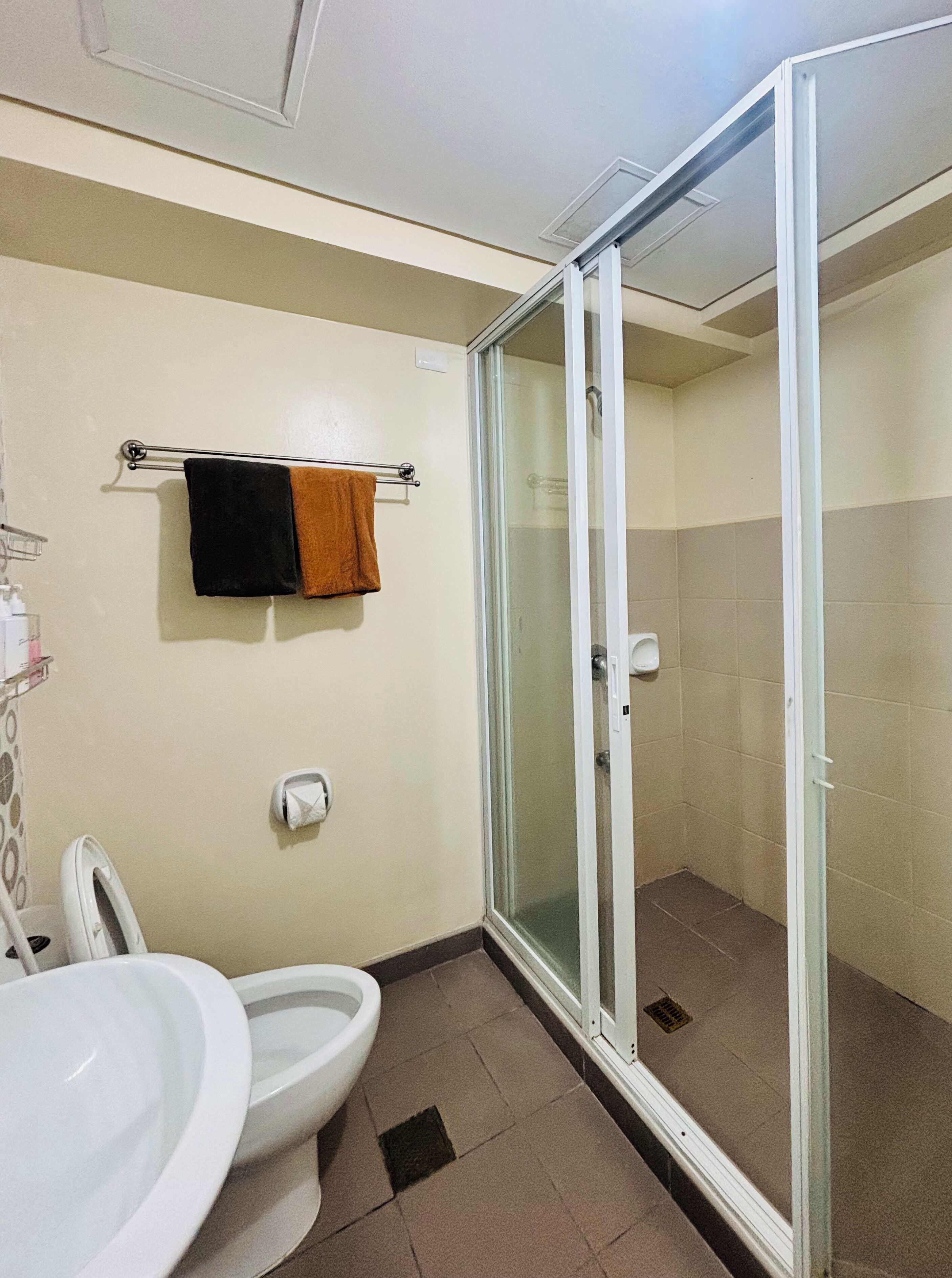 A bathroom with a toilet, sink, and glass shower enclosure.