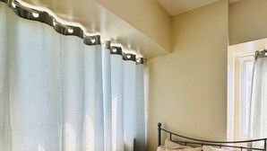 A bedroom with a bed, curtains, and a window. - Charming Iloilo City Condo for Rent - Entire House (Iloilo)