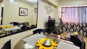 A dining area with a round table, chairs, and a central decorative sun-like object. There are hanging light fixtures above the table. - Charming Iloilo City Condo for Rent - Entire House (Iloilo)