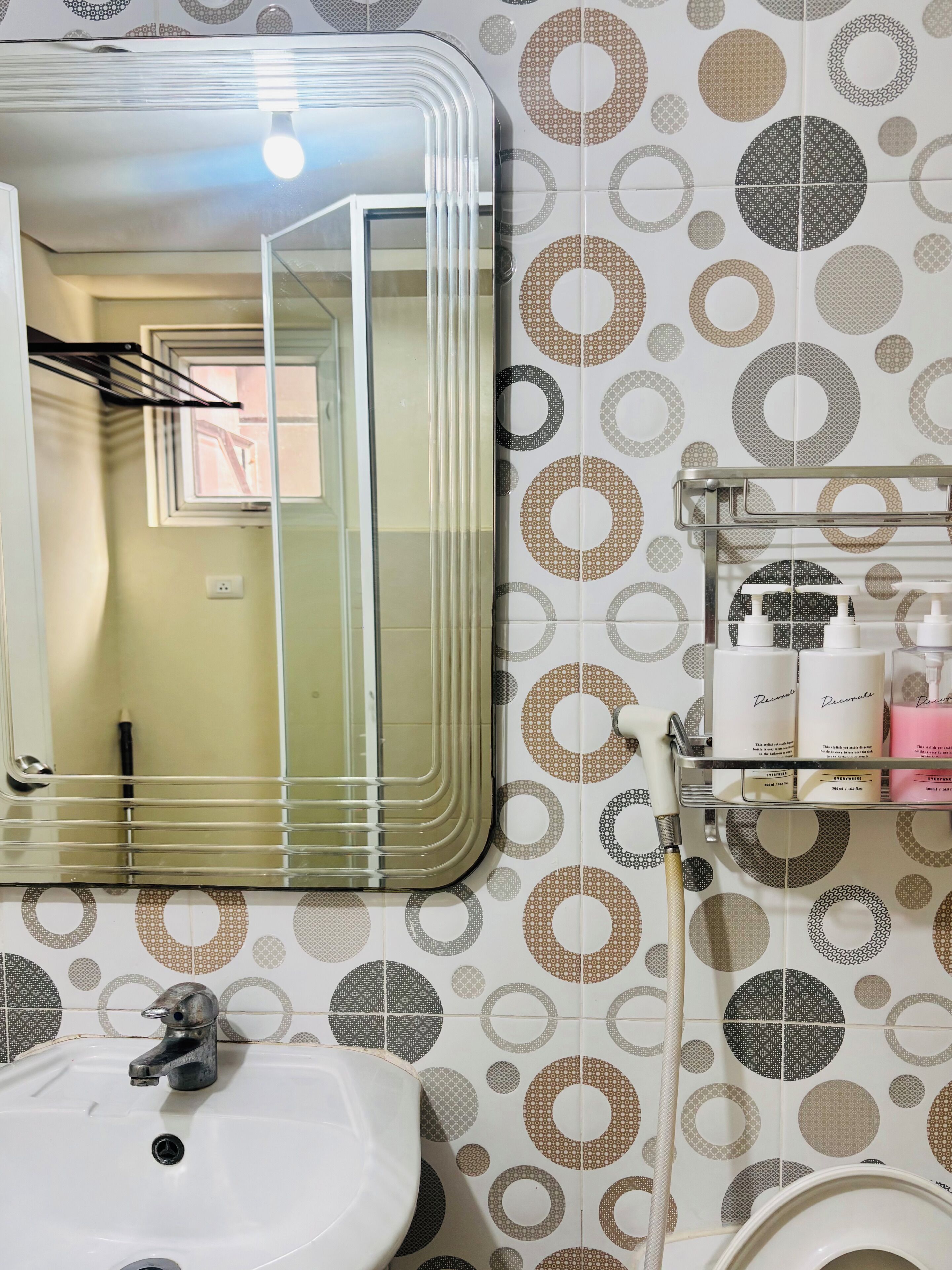 A bathroom with a sink, mirror, and toiletries shelf.