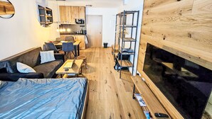 Ein kompakter Wohnbereich mit Küchenzeile, einer Couch, einem Esstisch und einem Fernseher.