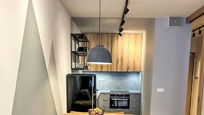 Ein modernes Wohnzimmer mit einem grauen Sofa, einem Esstisch mit Stühlen und einer Küche im Hintergrund.