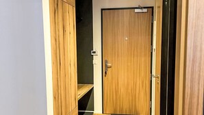 Ein Flur mit Holzboden, einer Holztür und einem Spiegel mit schwarzem Rahmen.