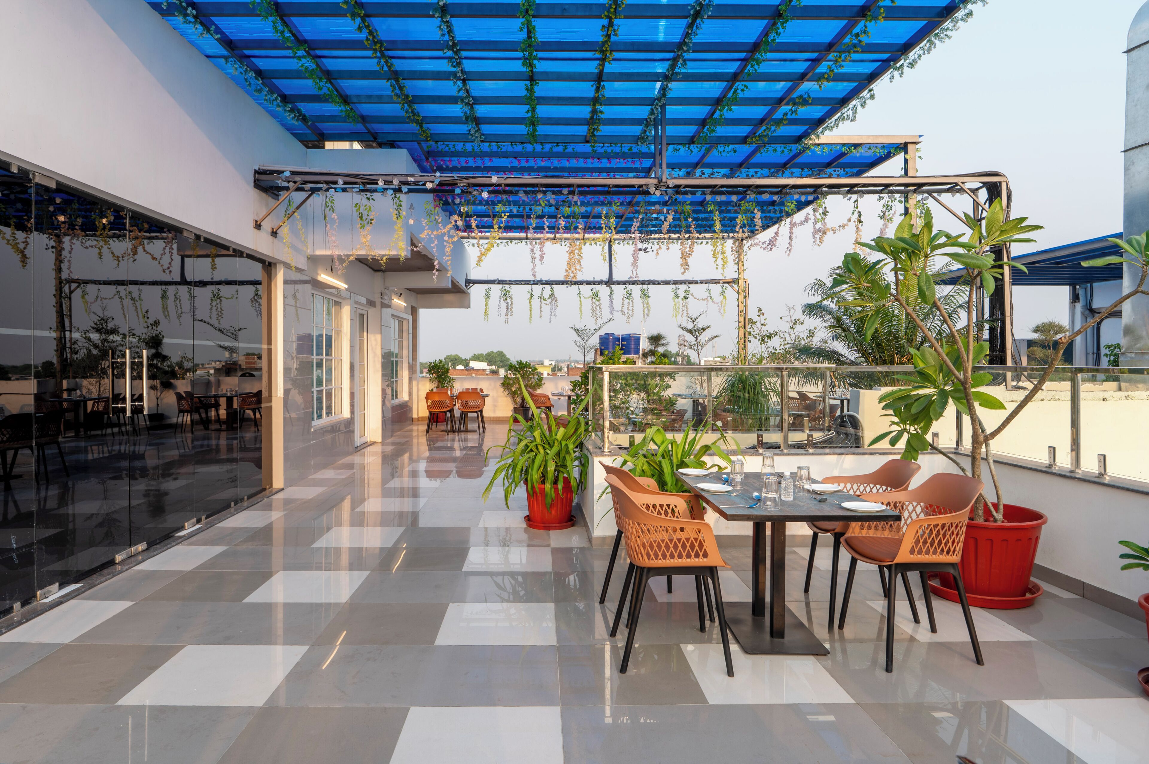 Terraza en la azotea con toldo azul, plantas en macetas y mobiliario exterior.