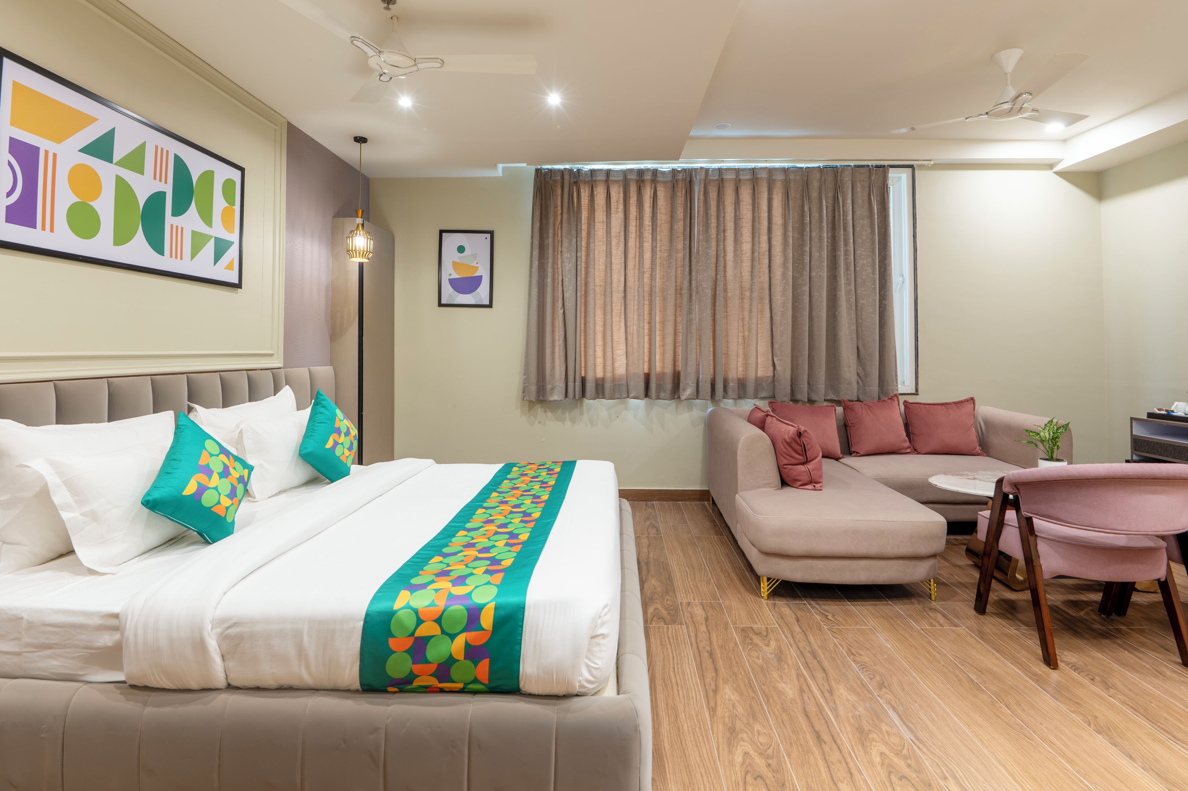 A modern hotel room with a bed, a sofa, a chair, and a desk.