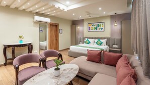 Moderni hotellihuone, jossa on sänky, sohva, tuoleja, pieni pöytä ja kattovalaisin.