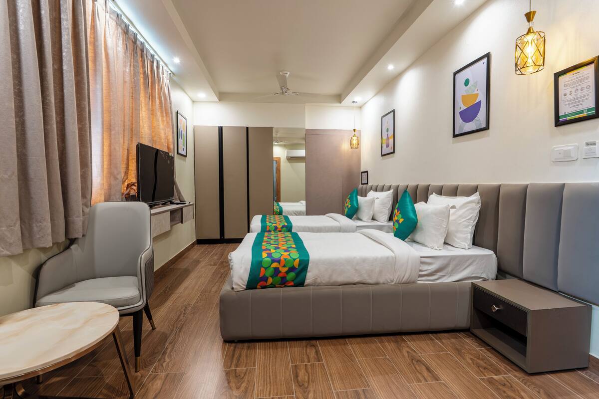 A hotel room with two beds, a sofa, a TV, and a desk.