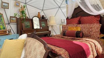 Een tent met een bed, een dressoir en een spiegel.