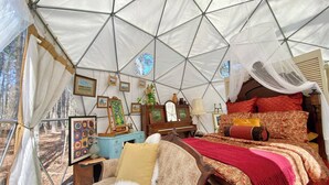 Una carpa con una cama, un aparador y cuadros en las paredes.