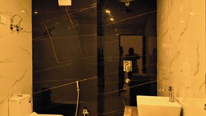 A bathroom with a toilet, a sink, and a shower. - The Opal Hotel (Greater Noida)
