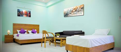 A bedroom with two beds, a sofa, a chair, a nightstand, and a ceiling fan.