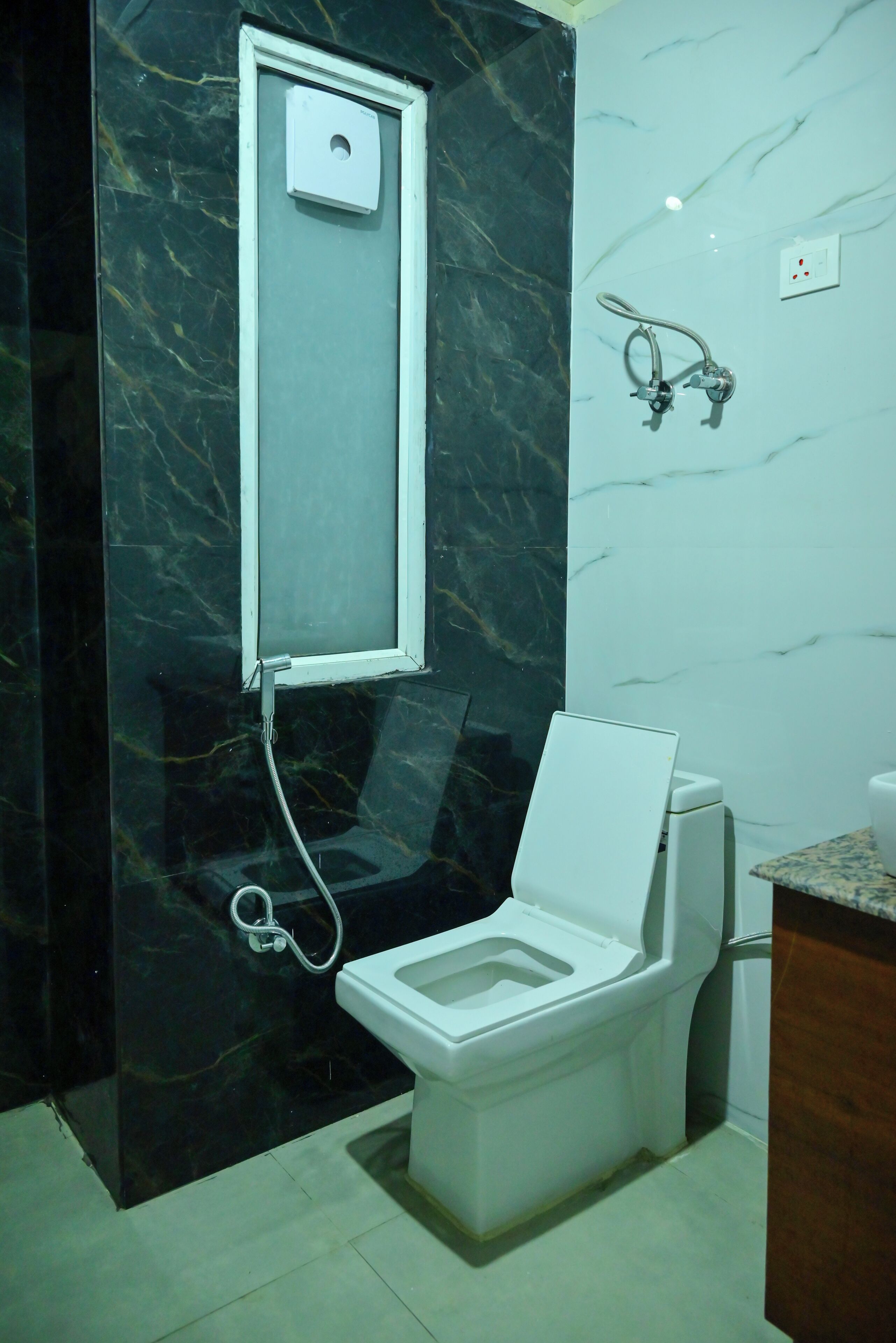 A modern bathroom with a toilet, a shower, and a marble wall.