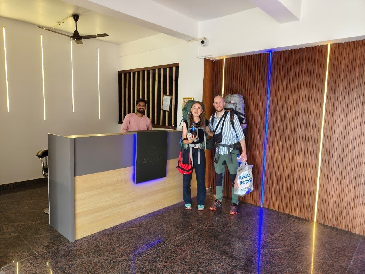 Una zona de recepción con un mostrador de madera, un ventilador de techo y un panel de pared de madera.