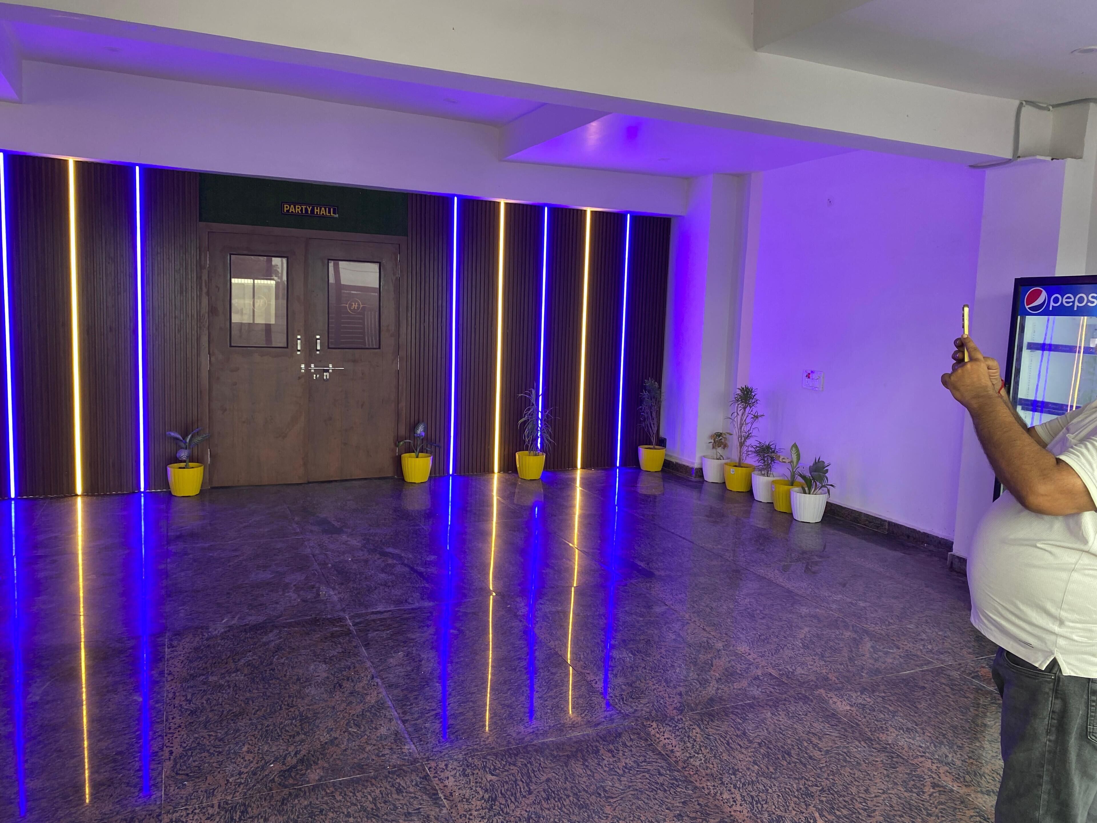 A hallway with a "Party Hall" sign, wooden doors, and potted plants.
