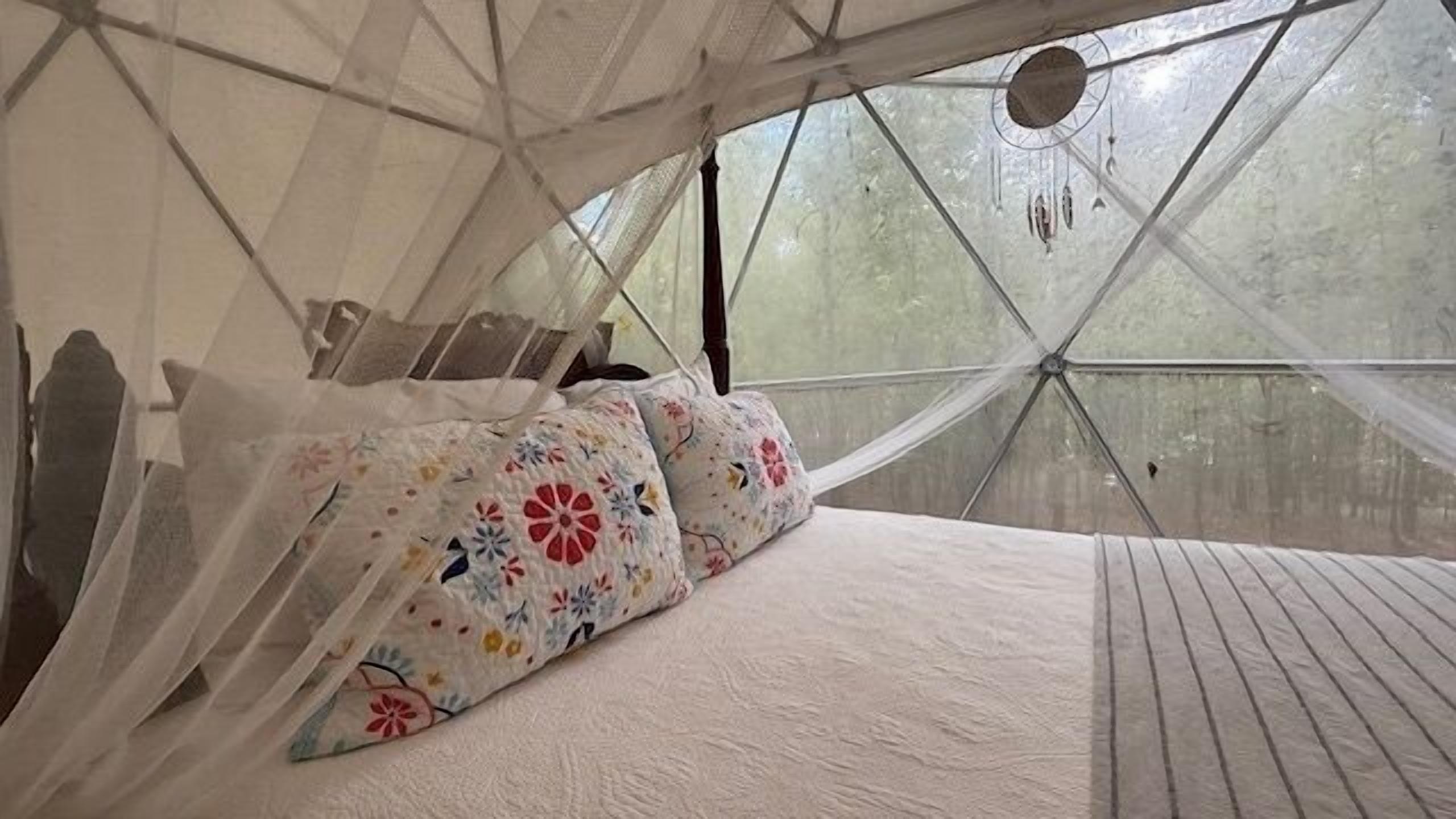 Een tentkamer met een bed, kussens en een baldakijn.