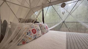 Een tentkamer met een bed, kussens en een baldakijn.