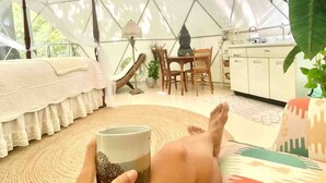 Una habitación con estructura de techo geométrica, una cama, una mesa de comedor con sillas y una zona de cocina.