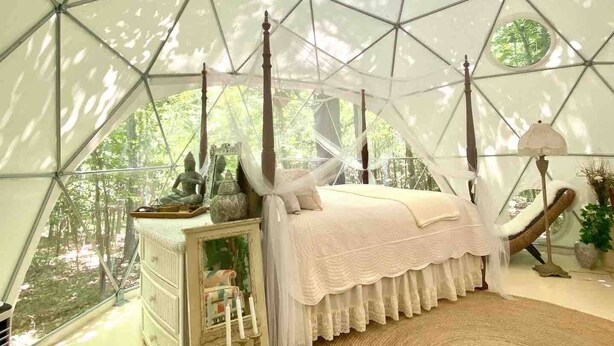 Una habitación con carpa, una cama, un aparador y un tapete circular.