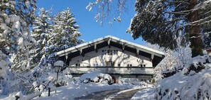 A traditional chalet with a balcony, surrounded by snow-covered trees and a clear sky. - Vacation apartment 70sqm with balcony, 1 bedroom, 1 living/bedroom, shower/WC, max. 5 persons (Ruhpolding)
