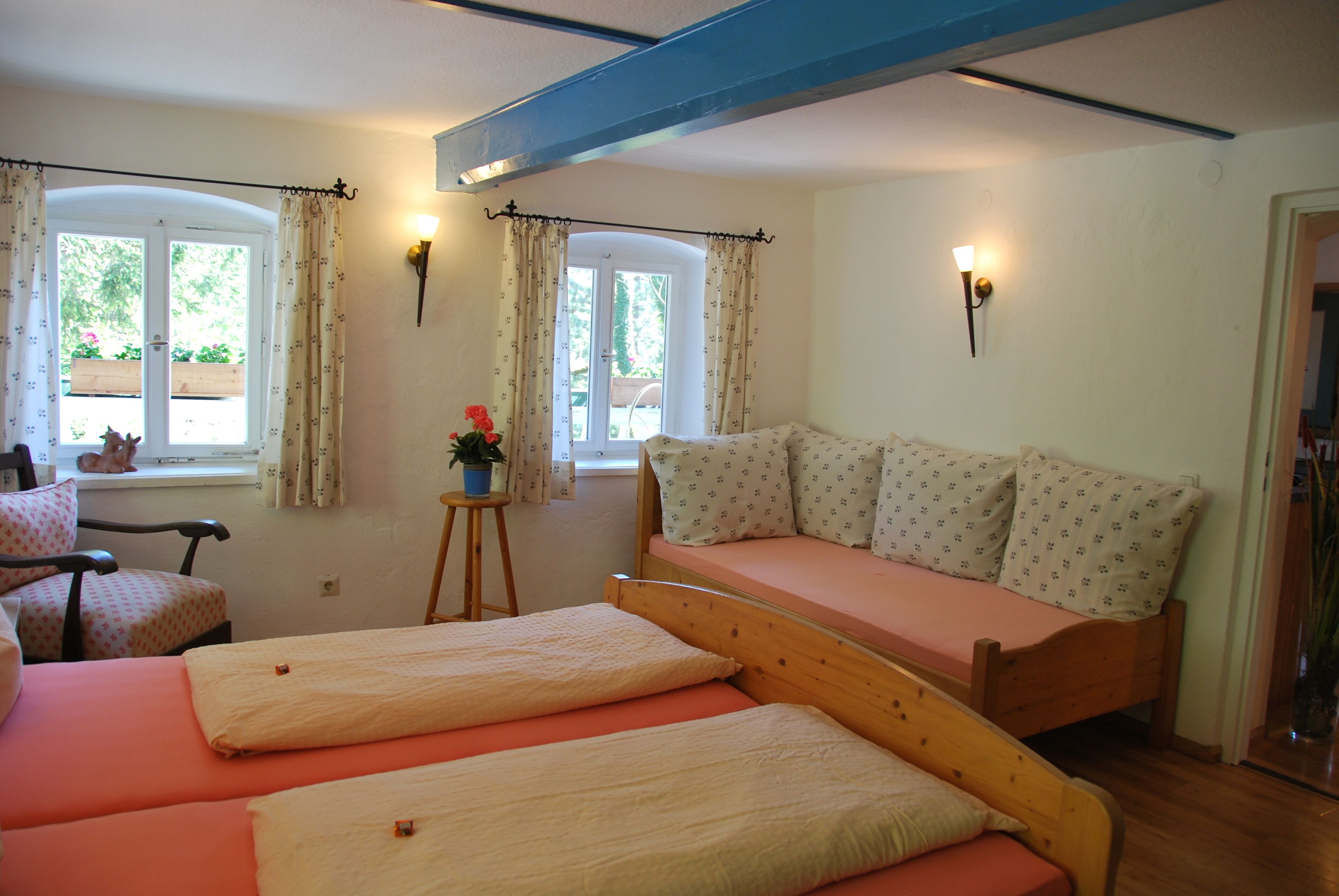 Una habitación con cama, una silla y una mesita con una planta.