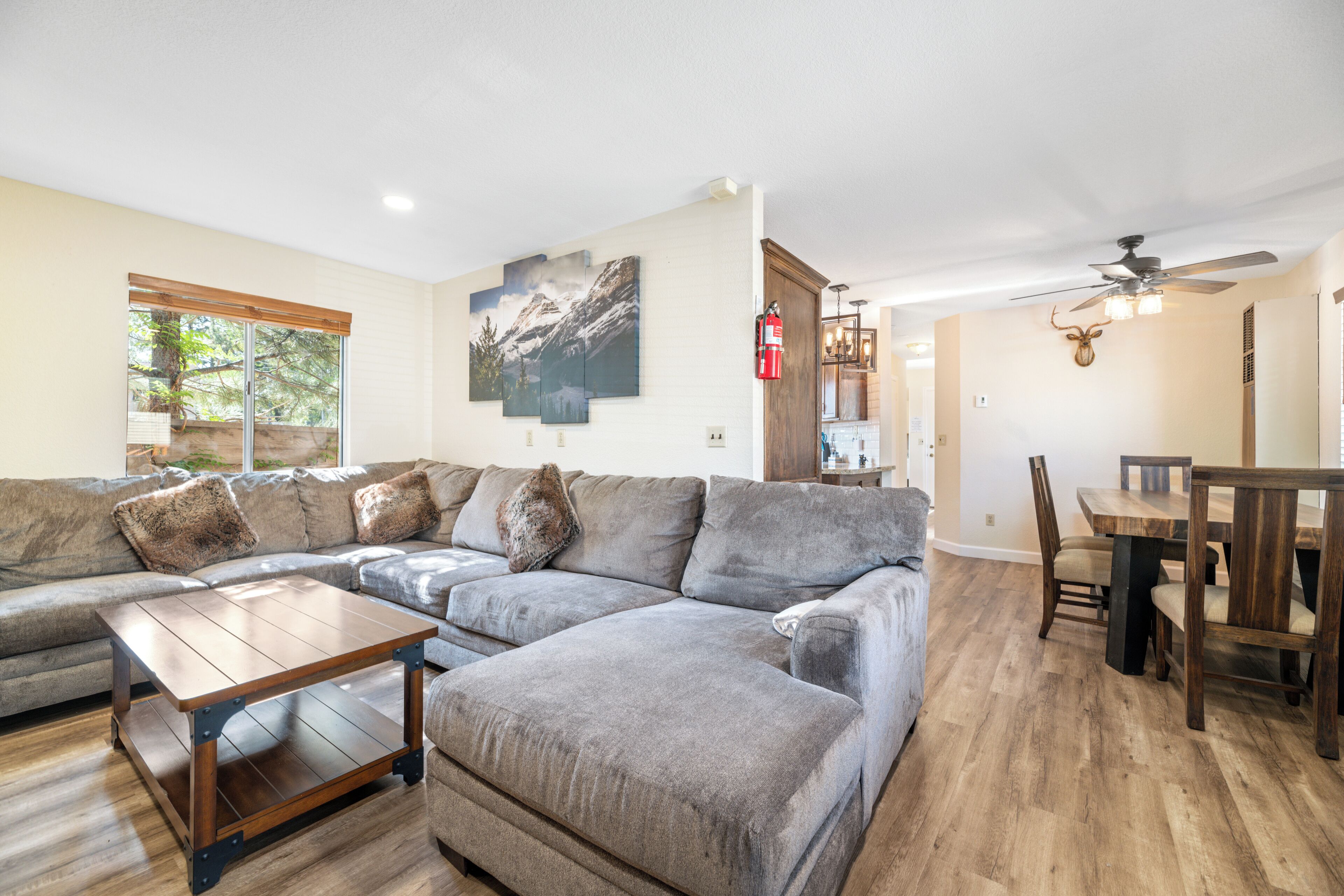 A living room with a sectional sofa, a wooden coffee table, and a dining area with a wooden table and chairs.